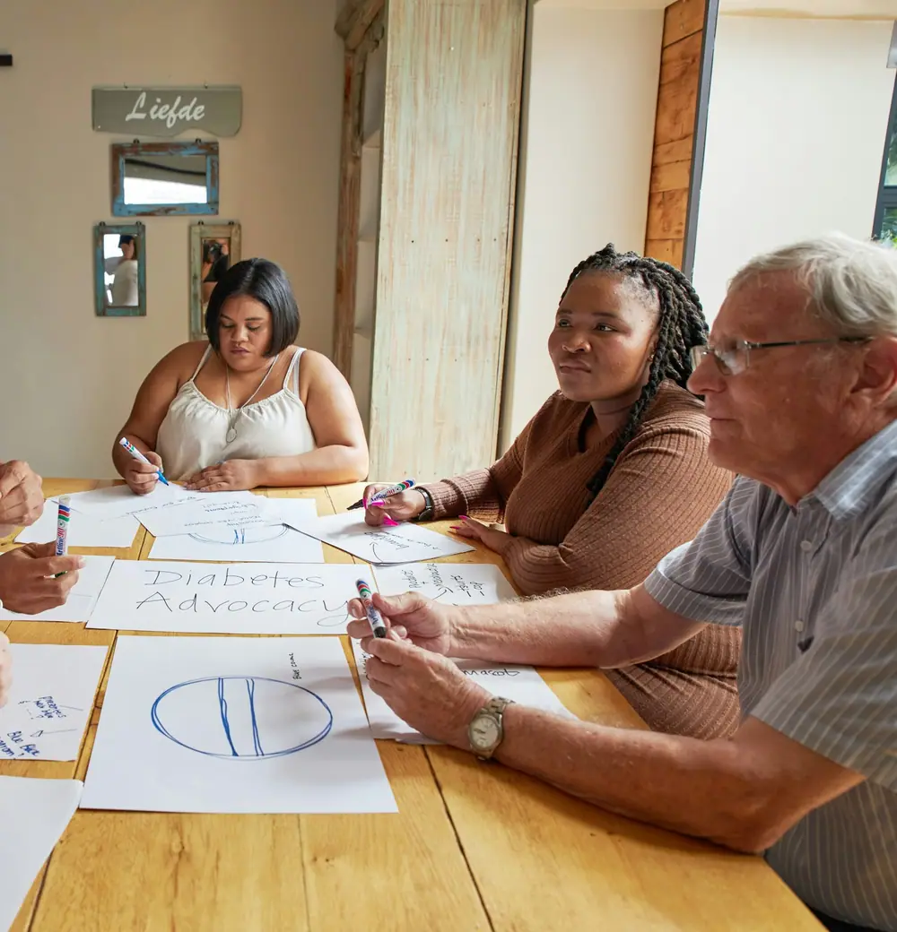 Volunteers chatting and smiling around a long table covered in papers